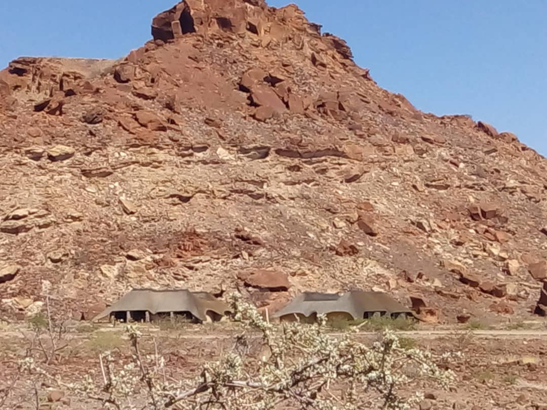 Damaraland thatched chalets beneath a rocky koppie